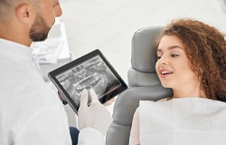 A young female with red, curly hair looks at her dental X-Rays shown by her dentist