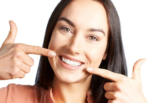 A woman pointing to her smile