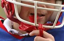 Child placing red athletic mouthguard