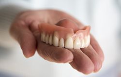 Hand holding a full denture