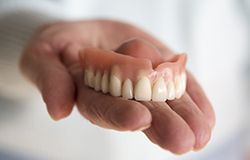 Hand holding a full denture