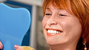 Senior woman looking at smile in mirror