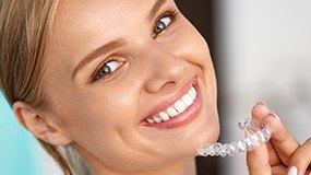 Smiling woman holding Invisalign tray