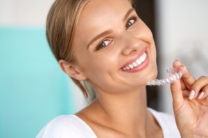 Woman holding Invisalign clear aligners