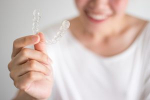 Woman holding Invisalign aligner 