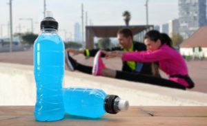 two sports drink bottles and two runners in the background stretching