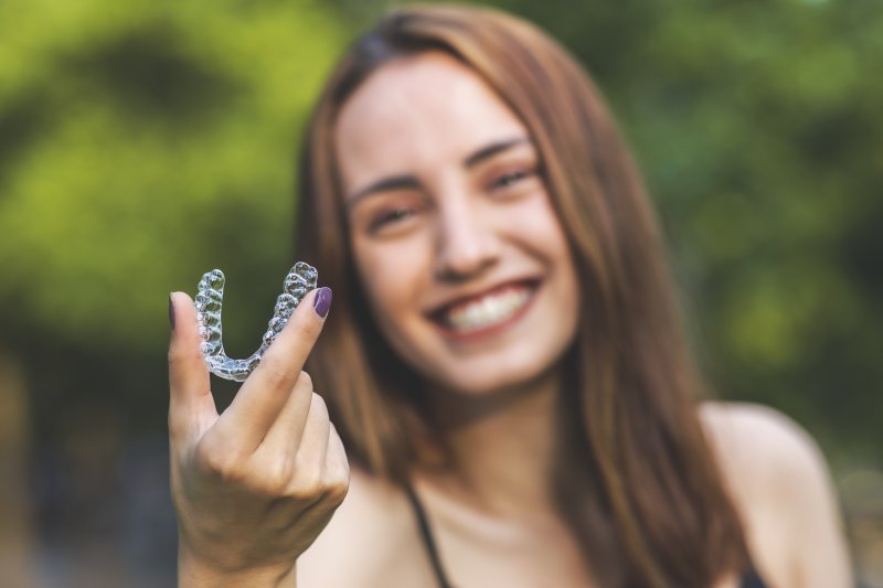 Woman holding up her Invisalign retainer