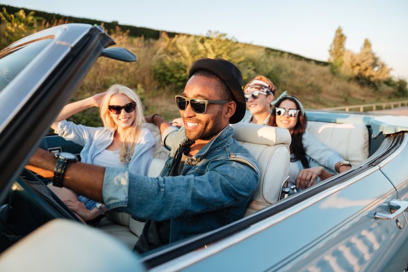 Friends smiling while driving down the highway on road trip