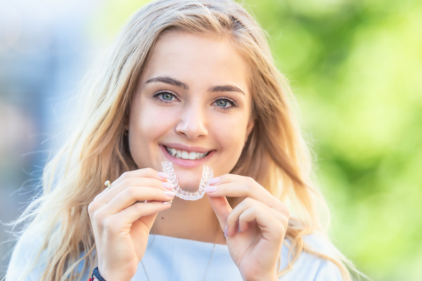 smiling woman holding invisalign aligner