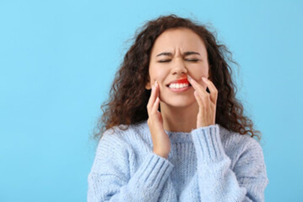 Woman experiencing mouth pain due to gum disease. 