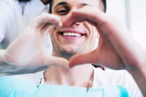 a man and his dentist forming a heart with their hands