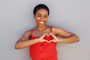 a woman smiling and forming a heart with her hands