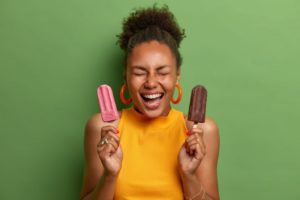 a woman holding two popsicles during the summer