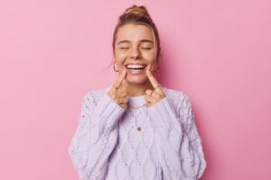 Woman smiling and pointing to her white teeth
